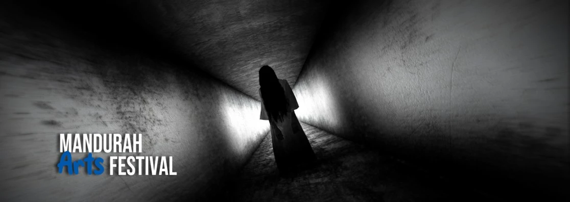A black and white picture of a long, dark corridor with a ghostly female figure standing eerily
